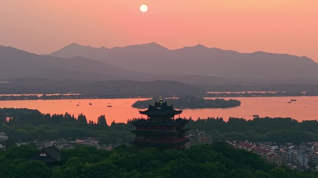Aerial view of Chenghuang pagoda at sunset over Xihu lake in Hangzhou featuring mountains and lush green trees