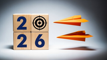 A creative concept of 2026 goals and targets with paper planes flying towards wooden blocks with numbers and a bullseye