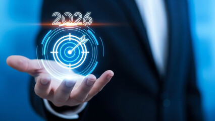 A businessman holding a glowing target with an arrow in his hand, representing a goal for 2026.