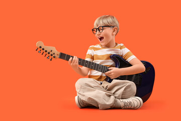 Fototapeta na wymiar Little boy playing electric guitar on orange background