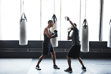 Men, boxer and coach with practice in gym for fight preparation, skill development or fitness. Boxing, athlete and personal trainer at health club for sparring, competition training and combat sport