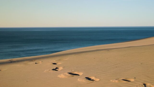 Minimal sand dunes slope gently toward Coast, forming clean diagonal lines, open space, calm water, and peaceful coastal atmosphere. Namibia. Africa