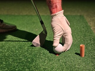 Player prepares to hit golf ball on putting green during indoor session at golf facility