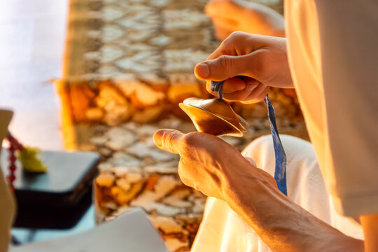 Cultural practice results in playing cymbals to anchor attention and maintain calm. Warm lighting emerges from decorative source enhancing inner stillness. selective focus