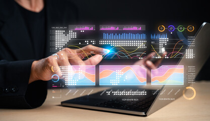A person interacts with digital data graphs on a laptop, showcasing technology and data analysis in a modern workspace.