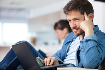 man smiling reads the screen of a laptop computer