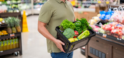 Man shopping with vegetable basket in supermarket. Grocery consumer. Man shopping at grocery store....