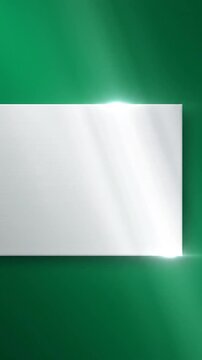 A brushed metal rectangular panel is lit by soft sunlight on a green background