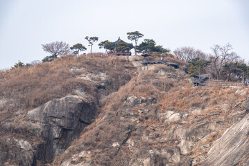 Scenic view of a rocky hill with sparse trees and a small pagoda on top in Seoul, South Korea