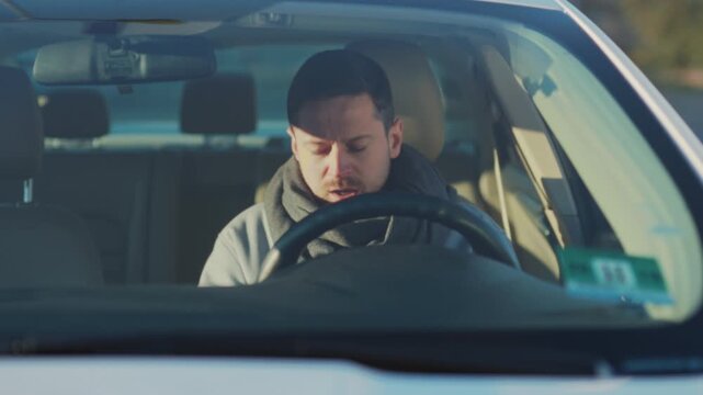 Person seated inside vehicle checks phone and glovebox before contemplating departure from vacant area