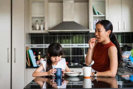 A mother and her daughter share a relaxed breakfast, sipping drinks and enjoying quality time