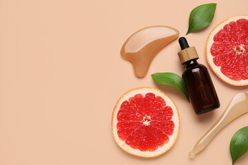 Obraz premium Composition with bottle of cosmetic product, facial massage tools and slices of grapefruit on beige background, closeup
