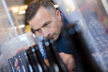 worker checking bottles on automated plant line