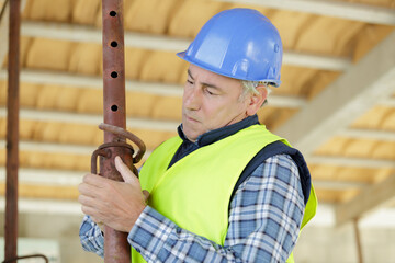 mature builder adjusting acrow prop © auremar