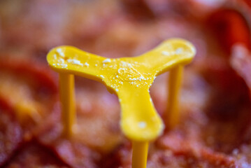 Close-Up of Yellow Pizza Saver on Pepperoni Pizza