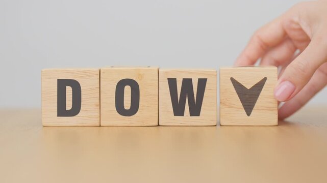Hand change wooden block of Dow Jones Index text to UP and Down arrow symbol icon. stock market index, trade, trade company in the United States, financial growth and Cut loss concept