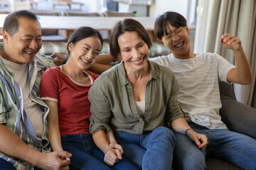Obraz premium Diverse family sitting on sofa in living room in casual clothes holding hands, wristwatch showing