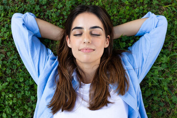 Young woman relaxing on grass with closed eyes