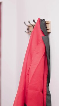 Person hand hang a stylish red jacket on hook