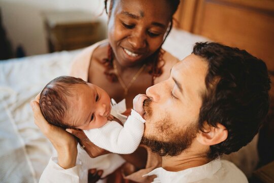 Black mom white dad kissing multiracial newborn baby