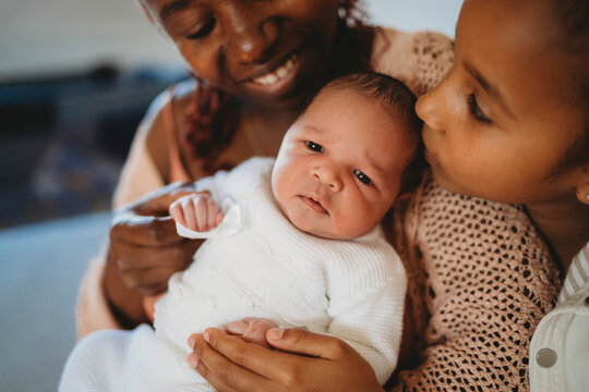 Multiracial family in bed at home black mom holding baby