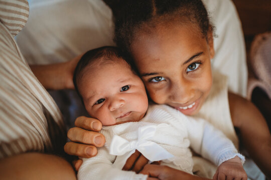 Multiracial girl holding newborn baby brother