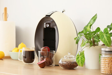 Modern coffee machine with capsules and beans on counter in kitchen