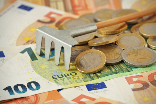 Rake with euro coins and banknotes - Concept of economy and making money