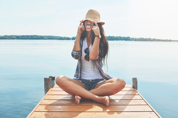 Lake, hat and playful woman on bridge for holiday, weekend travel trip and summer break destination. Tongue out, space and happy person with cap for sun protection, vacation and tourism in Indonesia