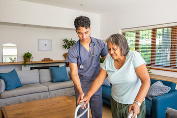 Hispanic male nurse in scrubs with stethoscope supporting senior woman with walker