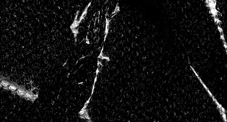 High contrast bubble wrap texture on black background with glowing light reflections. Abstract plastic pattern, futuristic industrial surface, dramatic lighting, creative packaging concept.