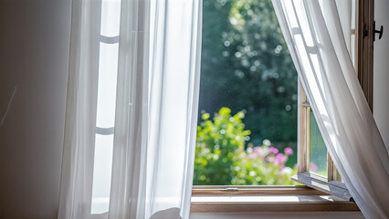 Open window with white curtains blowing in wind and view of green garden summer morning concept fresh air home interior © Celt Studio