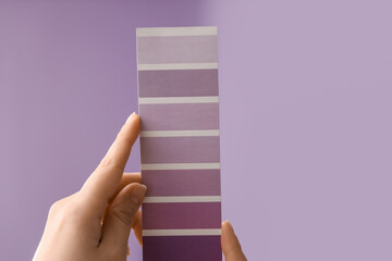 Female hands with violet paint palette swatches on lilac background