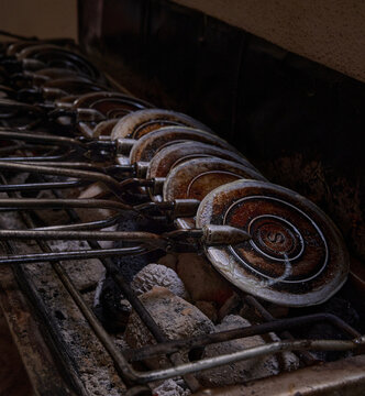 Traditional Kuih Kapit Iron Moulds Heating Over Charcoal Fire for Festive Cookie Making