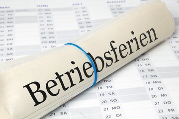 Betriebsferien: Symbolische Zeitung mit der Aufschrift BETRIEBSFERIEN auf einem Kalender