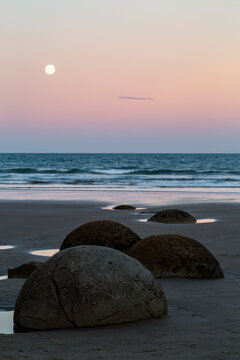 Moeraki boulders and moon at dusk on beach