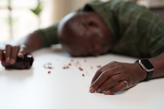 Unconscious person lying face down with scattered medicine and an overturned pill bottle, illustrating themes of drug overdose, suicide attempt, and mental health struggles