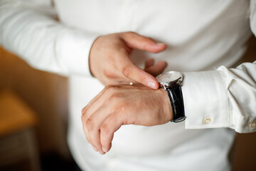 A man in a suit is wearing a watch and adjusting his jacket. The image has a blurry quality, which gives it a sense of motion and action. The man's focus on his watch
