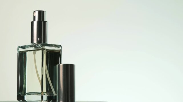 Perfume bottle rotating then stopping front facing in studio light, with clean background and copy space on the right.