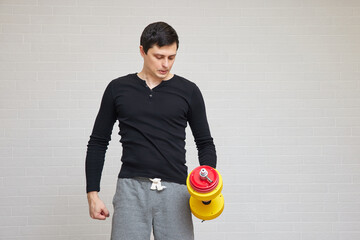 Man holding dumbbell in hand, reflecting on home exercise