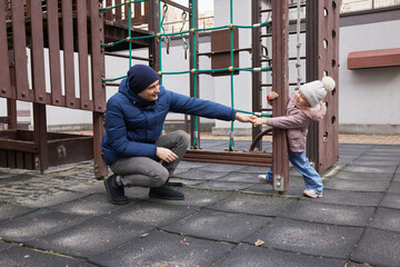 Father and daughter enjoying time together on a rubber playground during winter
