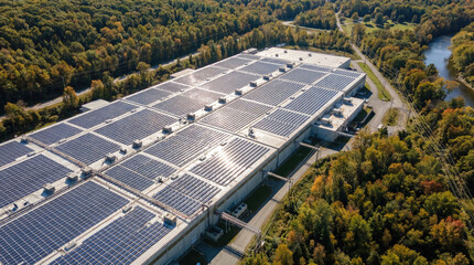 Aerial view of large industrial building with solar panels roof, surrounded by trees and nature