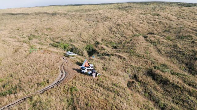 Aerial View of Remote Mountain Campsite with A-Frame Cabin and Off-Road Vehicles