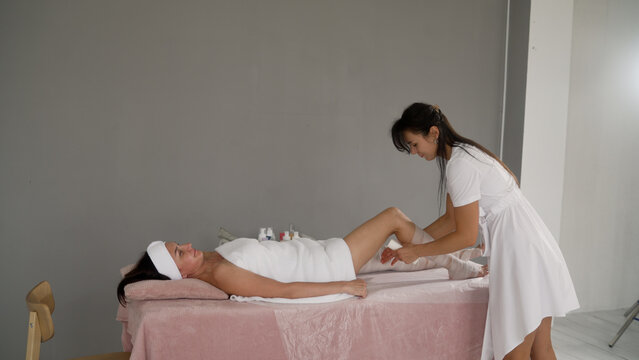 Woman receiving anti-cellulite body wrap spa treatment
