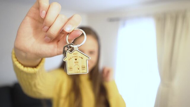 A joyful woman holds up the key to her new home, beaming with excitement. The focus is on the shiny key, symbolizing new beginnings, dreams realized, and a fresh chapter in life.