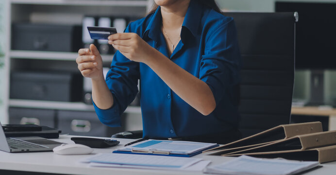 Young businesswoman is holding two credit cards with a worried expression, trying to decide which one to use to pay off her debt