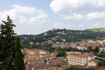 Naklejka premium Photo of the beautiful city of Verona in Italy showing a view of houses and homes on the hillside that over looks the historical city on a sunny blue sky day with clouds in the sky