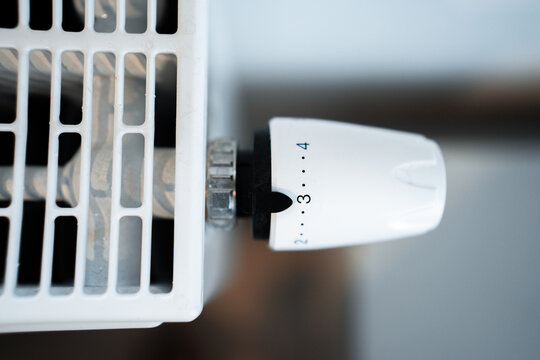 Radiator thermostat knob close-up on setting 3 &mdash; white thermostatic valve controlling home radiator for energy-efficient heating and temperature regulation