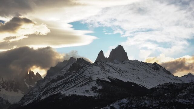 Cinematic timelapse of vibrant orange clouds rapidly moving over Mount Fitz Roy and Cerro Torre in Patagonia after sunset.