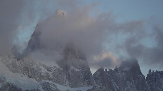 Cinematic timelapse of mount fitz roy during sunrise with fast moving clouds and warm orange light covering the granite walls. El Chalten, Patagonia